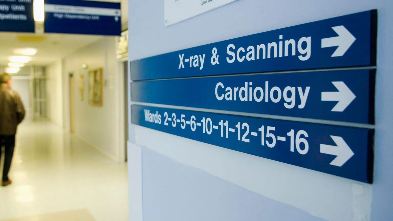  A stock image of a hospital sign pointing towards cardiology. It is a blue sign with white font. Above it a sign reads 