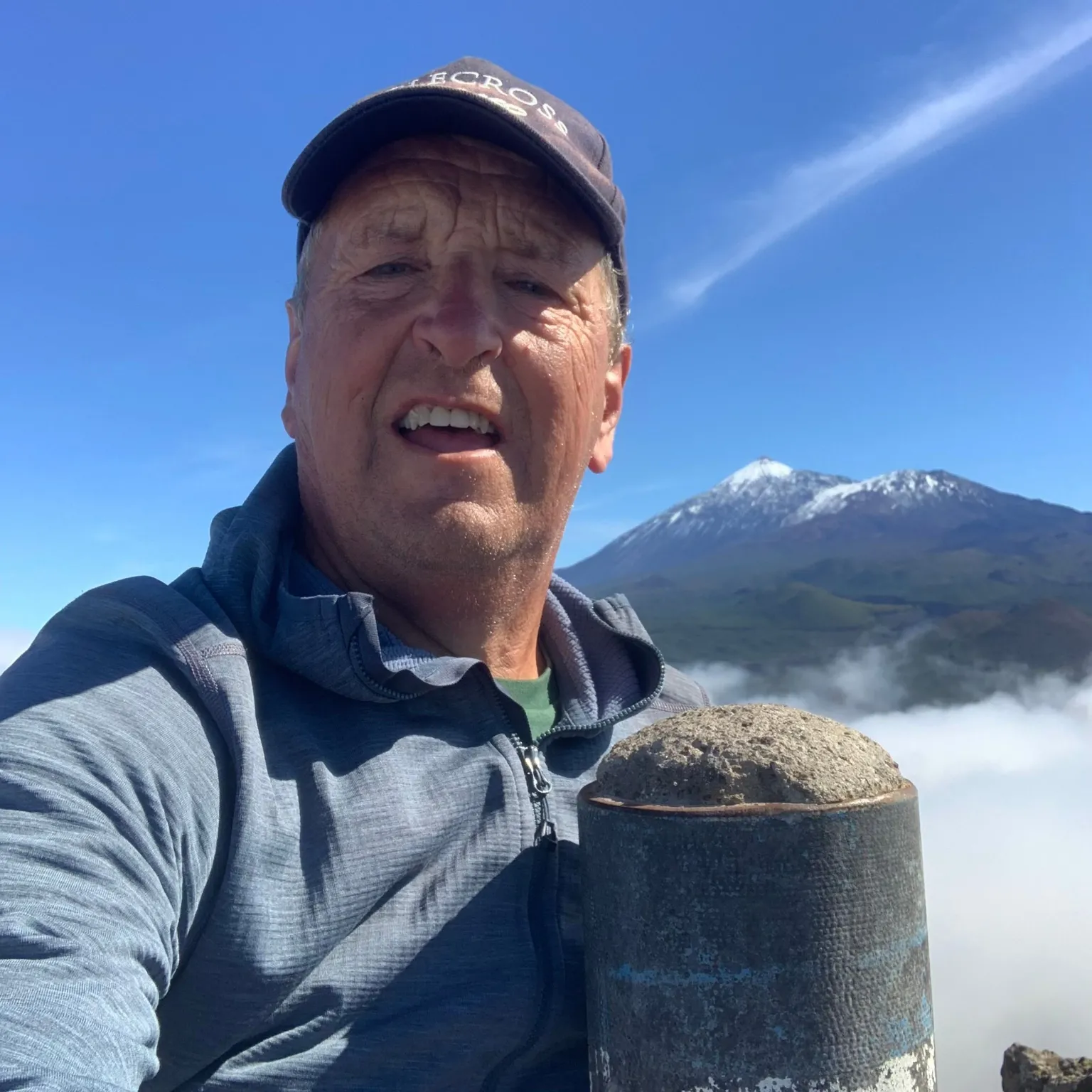 David McNicol A man in a baseball cap with a blue top on standing at the top of a mountain or hill