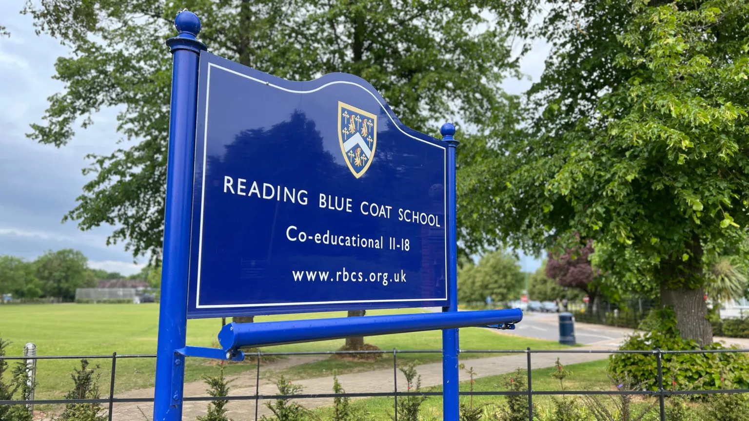 A blue sign reading Reading Blue Coat School - co-educational 11-18 with their web address underneath