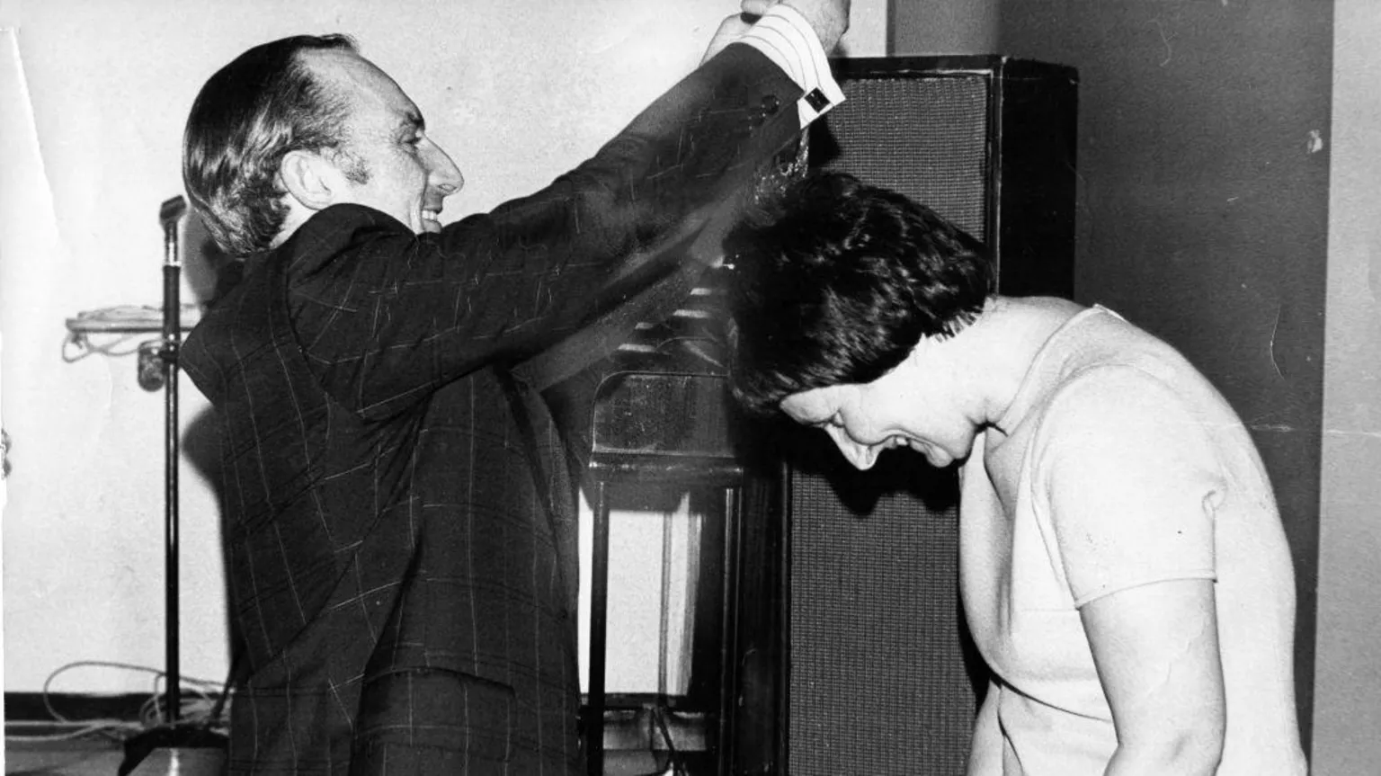 Kenneth Black Mary being presented with a medal by a man wearing a suit. She has short dark hair and is wearing a white top.