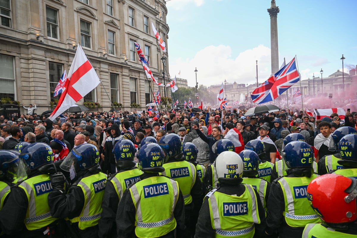 Police in riot gear watch as thousands of people wave England flags and the union jack at the Unite the Kingdom rally in London.