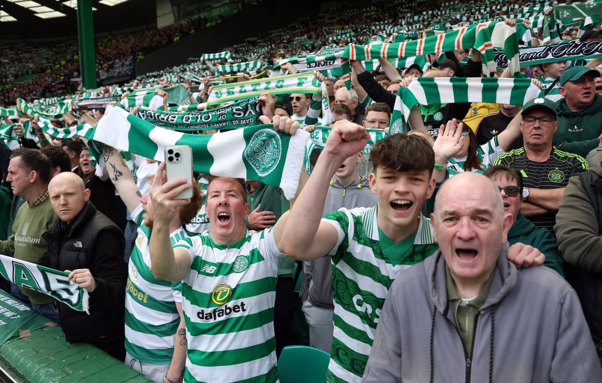 Celtic fans hold their scarves aloft in the stands.
