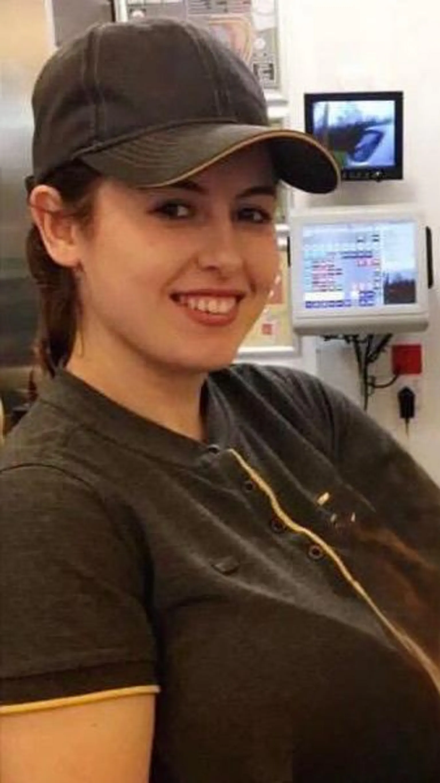 Lucy Wall Lucy is wearing a McDonald's uniform and baseball cap and is pictured in the drive-through area of the business, with screens on the wall behind her.