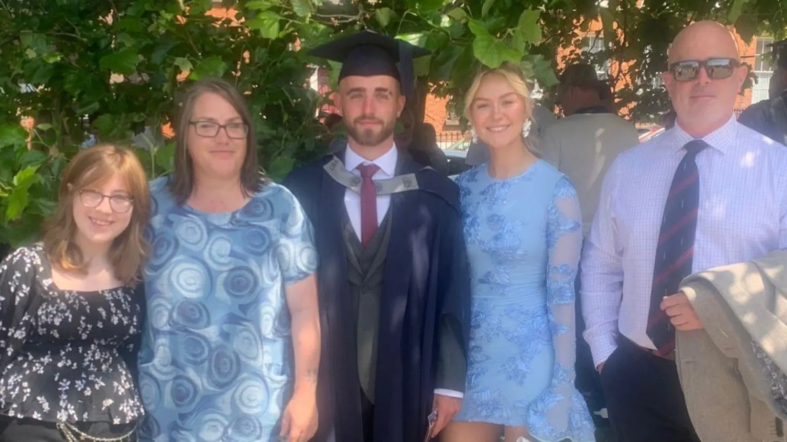 Tom Cowan Tom Cowan pictured with four of his family members at his graduation at Liverpool University. He stands in the middle wearing a three piece suit, navy cap and gown. 