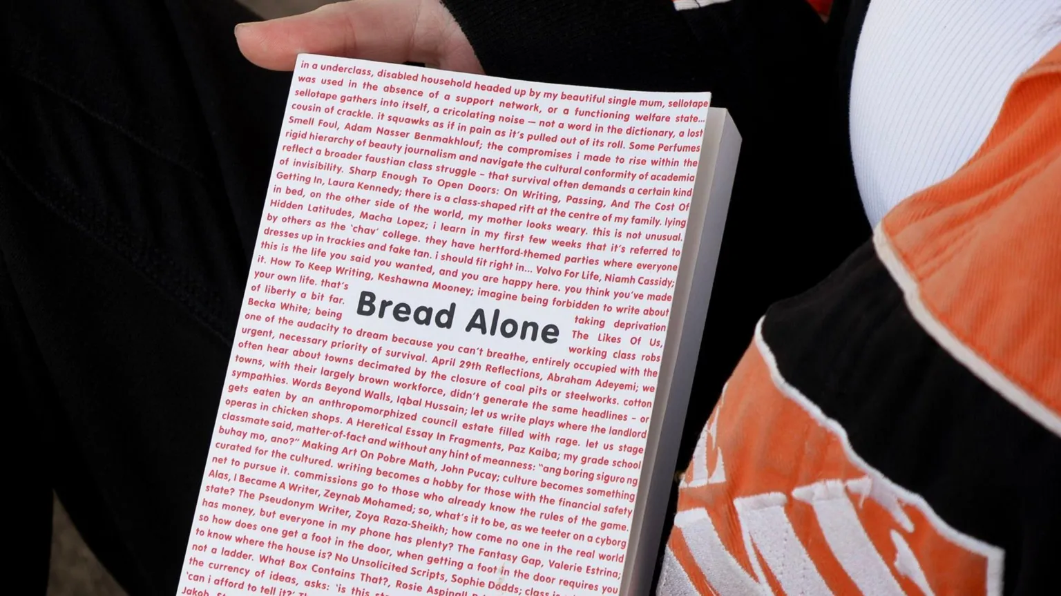 A white book with the works 'Bread Alone' written in the middle in black, surrounded by red words.