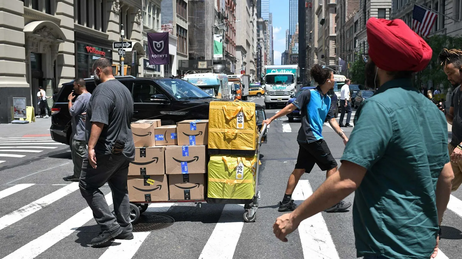  A worker crooses the road with a large pile of packages on a trolley in New York, US, on Tuesday, July 8, 2025 