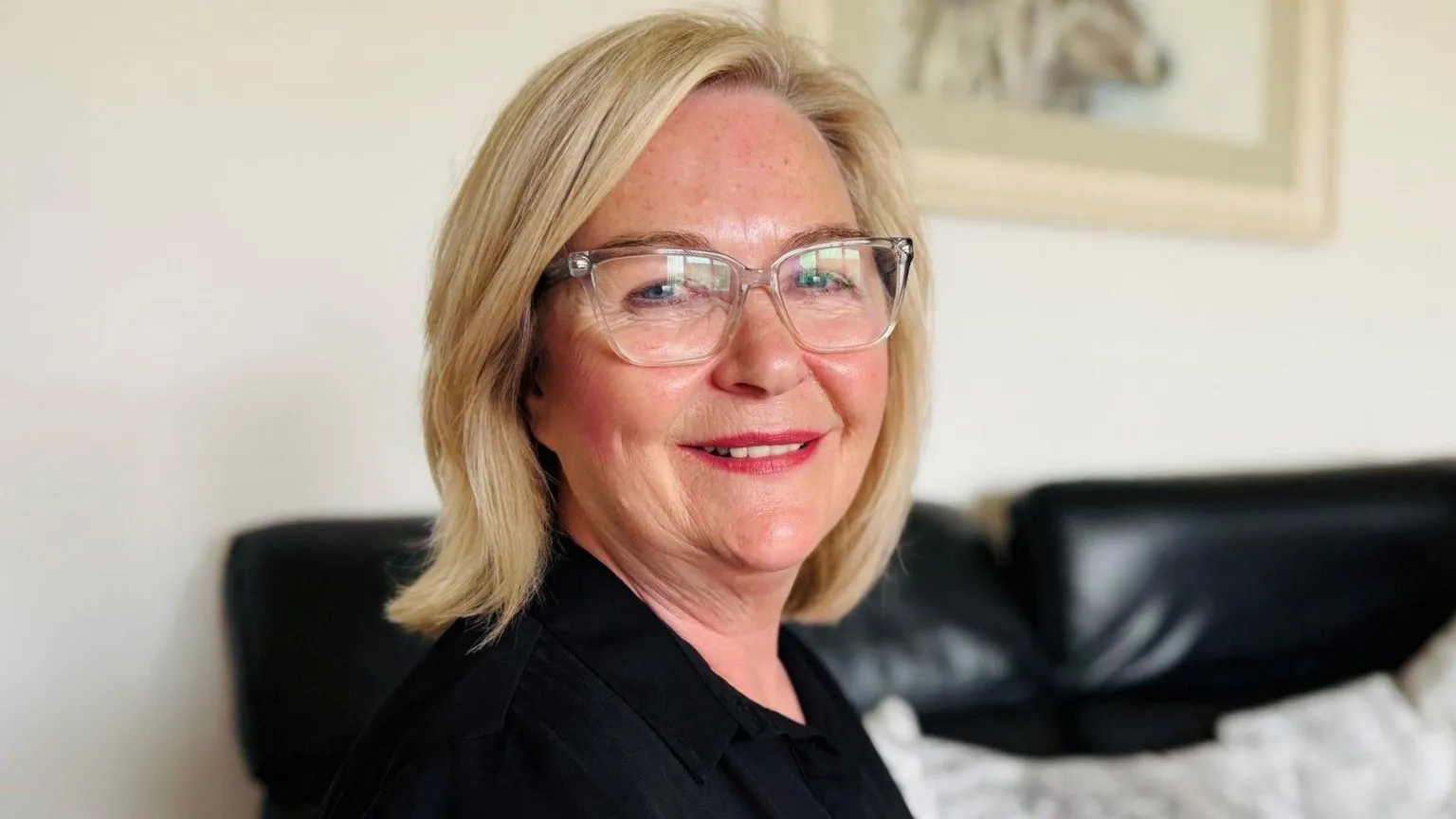 Brenda Young, a woman with shoulder length blonde hair and glasses smiling at the camera.