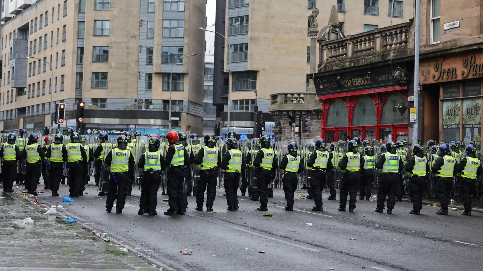 The view from behind of a row of police, most with shields, as Celtic fans take over the Trongate area of Glasgow to celebrate winning the league