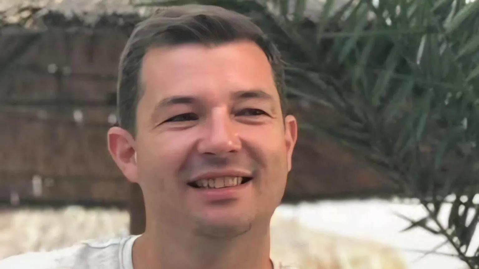 David Lusby A smiling man in a white tshirt sits in front of a brick wall. He has short dark hair