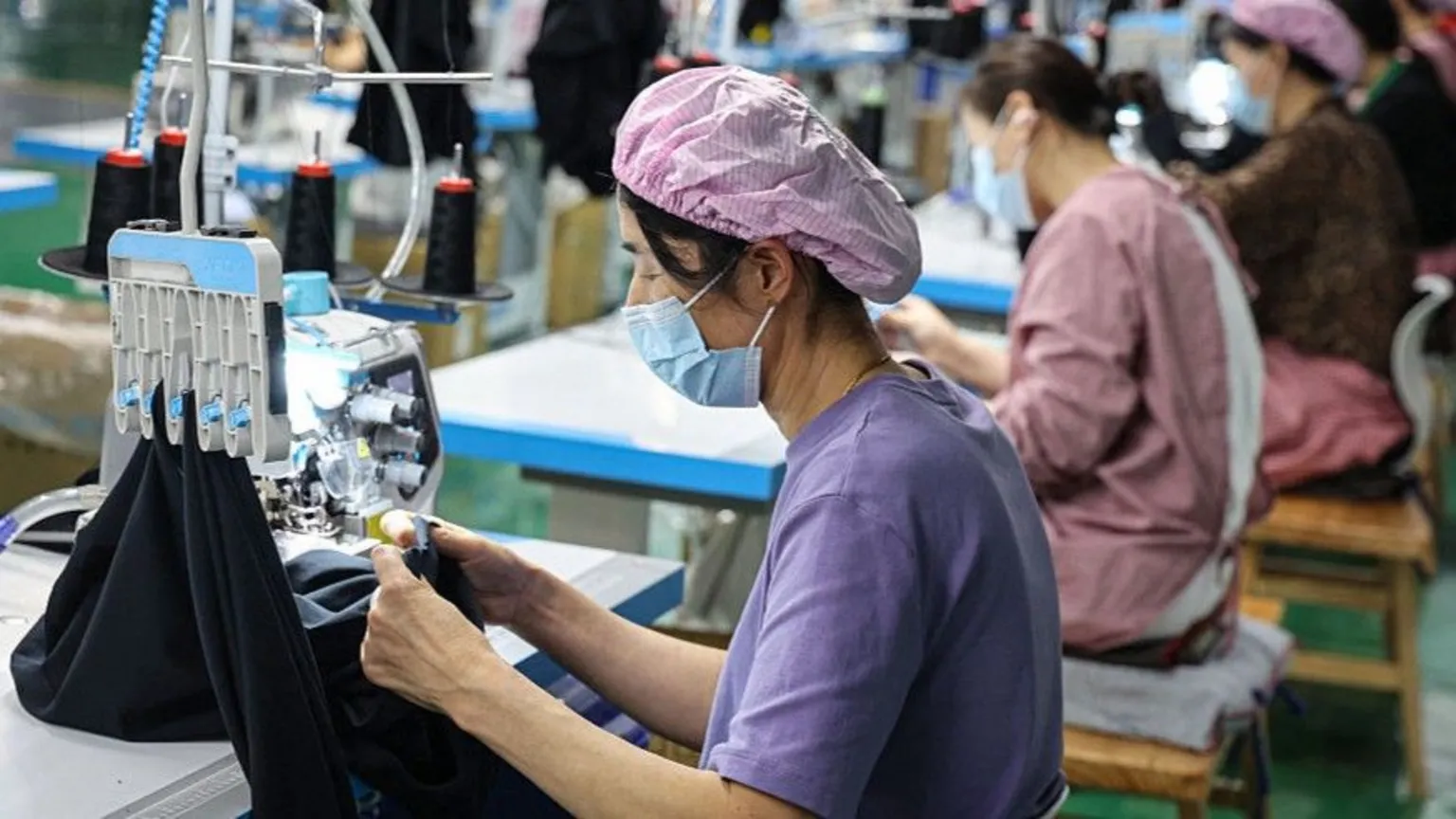A factory worker in China works at a sewing machine