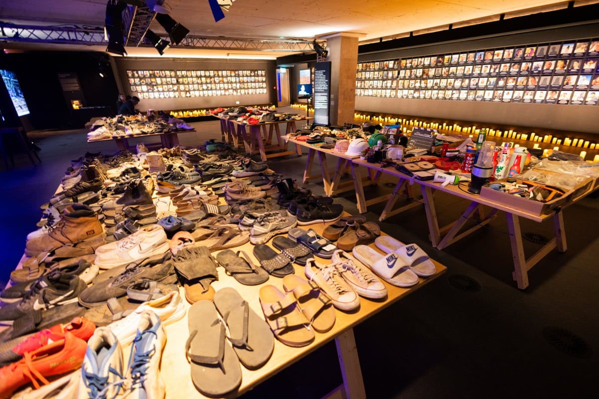 Room from exhibition including table of shoes with other belongings around