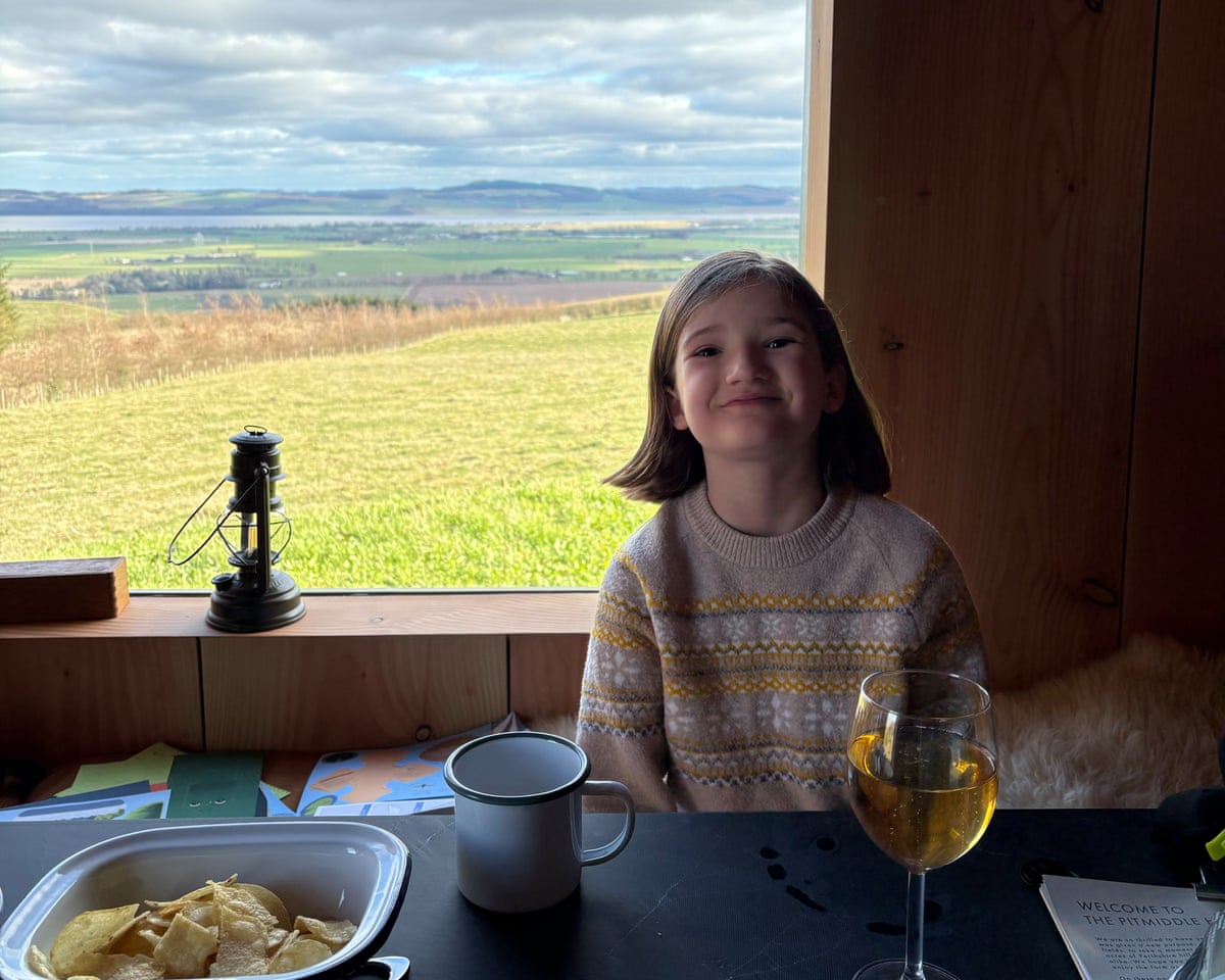 Smiling young girl and glass of apple juice and window with lovely view