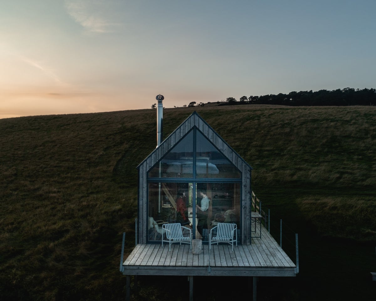 Modern hut with decking on hillside at dusk