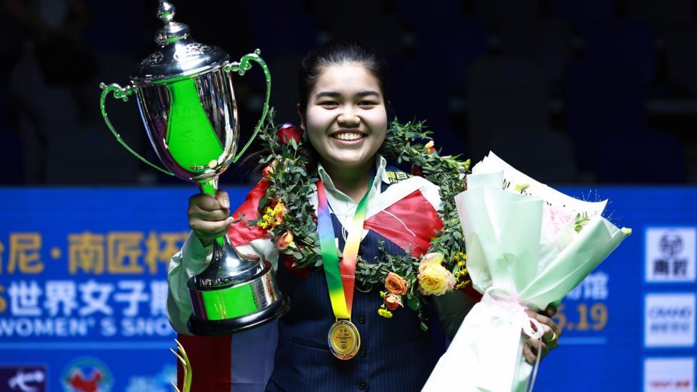 Women's world snooker champion Panchaya Channoi holds the Mandy Fisher Trophy and a bouquet of flowers