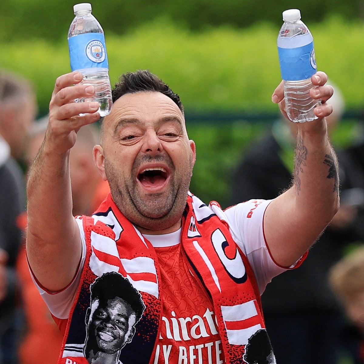 Arsenal fan holding bottles of water with the Manchester City badge on outside the stadium.