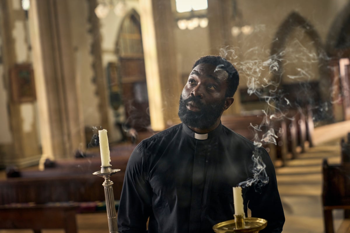 A priest holds a smoking candle in a church.