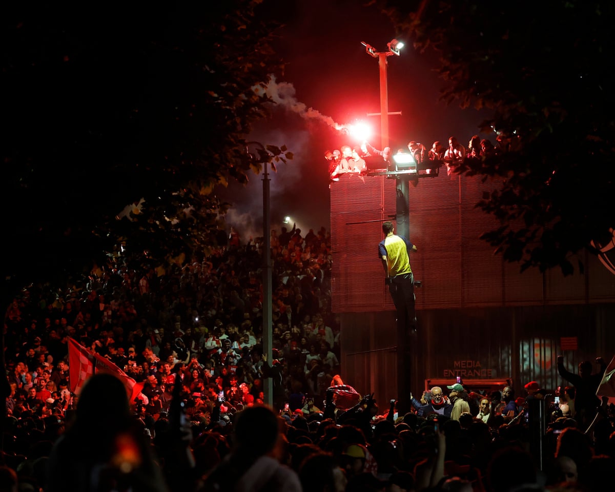 Large crowd at Emirates Stadium with a flare lit