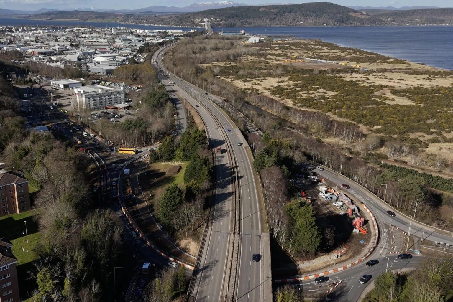 An aerial view of the Raigmore Interchange. It is a large structure featuring an oval shaped roundabout with a flyover going over the top of the roundabout and a grassy area.