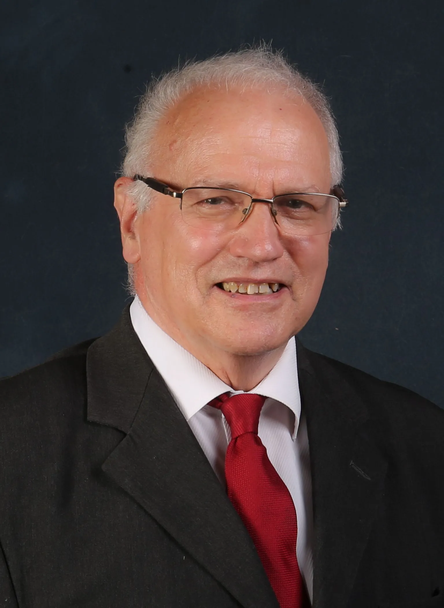 Fife Council A man with receding grey hair and glasses in a dark suit jacket with a white shirt and red tie