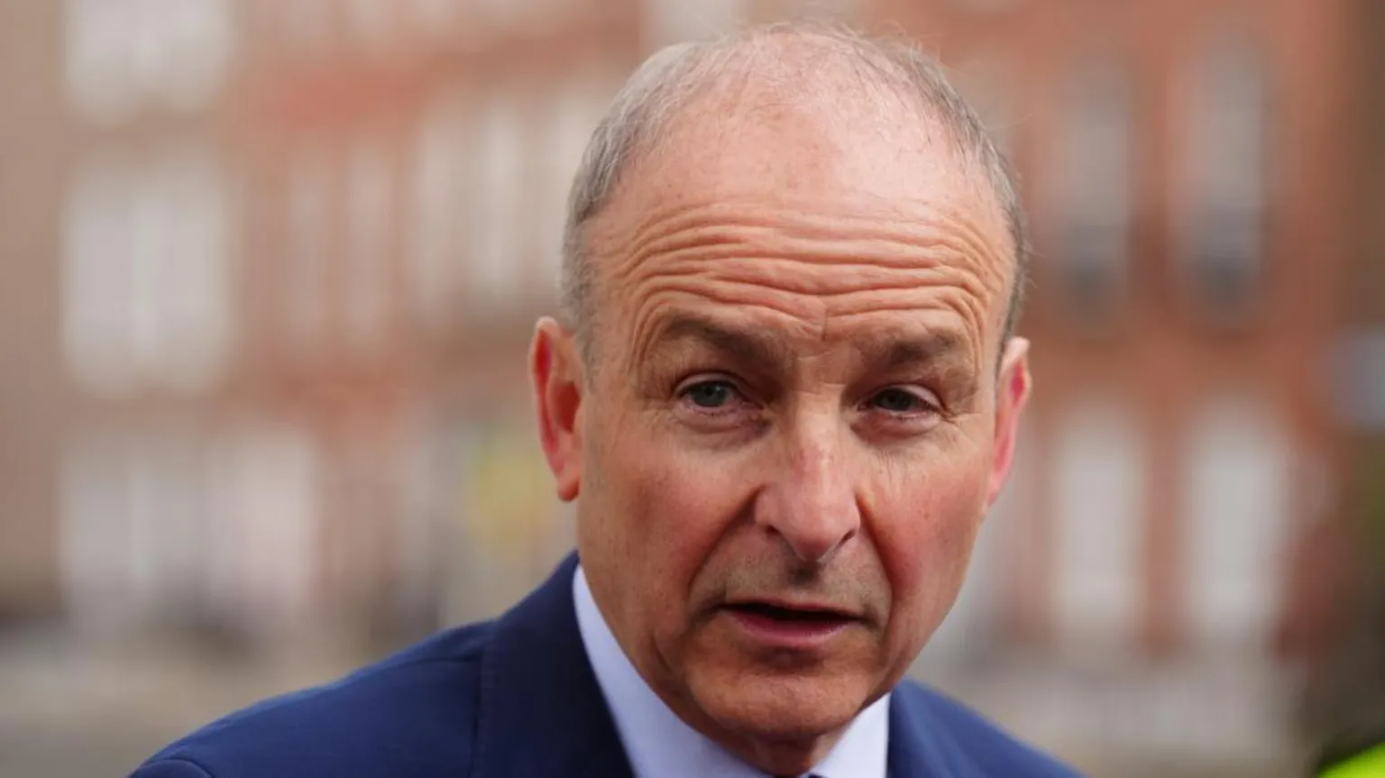  Martin is photographed looking shocked. he has thin grey hair and is wearing a navy suit jacket and white shirt.