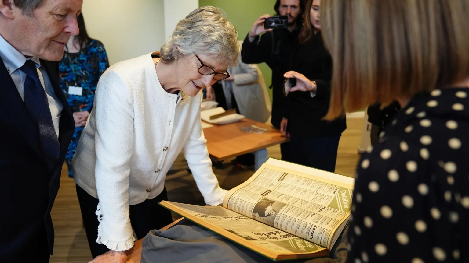 Irish president Catherine Connolly during a visit to Leeds University, as part of her official visit to the UK. She has short white hair wearing glasses and a cream cardigan. She is leaning over a table looking at a large open book. Other people are around her.
