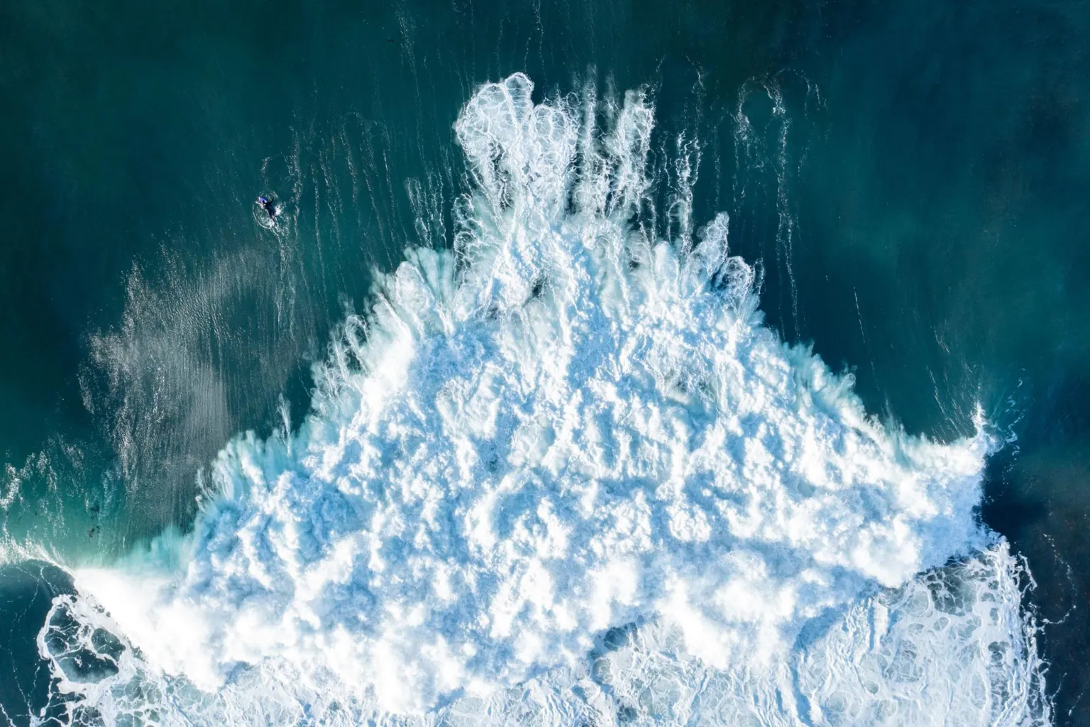 An aerial view of white, frothing surf as waves crash into the north Caithness coast.