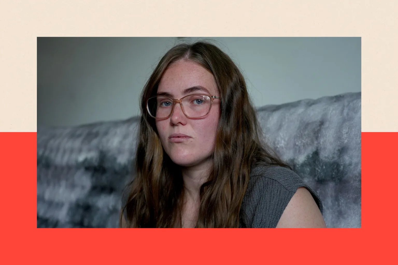 A photo showing Chereece sitting on a grey sofa in front of a pale wall. She has long dark hair and is wearing glasses and a grey top.