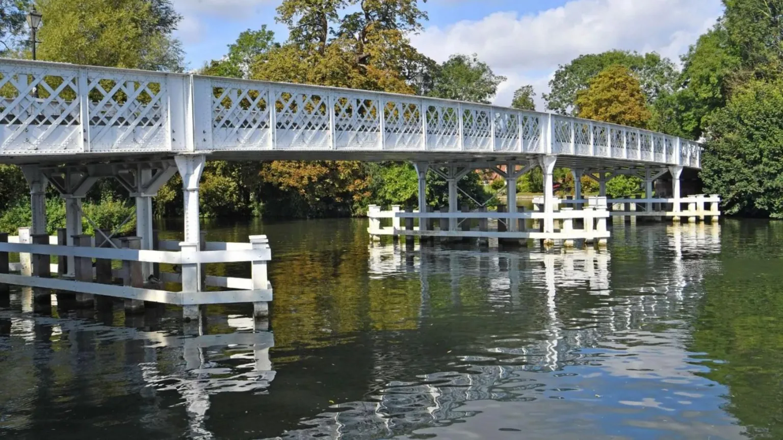 Pangbourne Parish Council River Thames at Pangbourne River Meadow - a white bridge stretches over the water and can be seen reflecting on the surface.