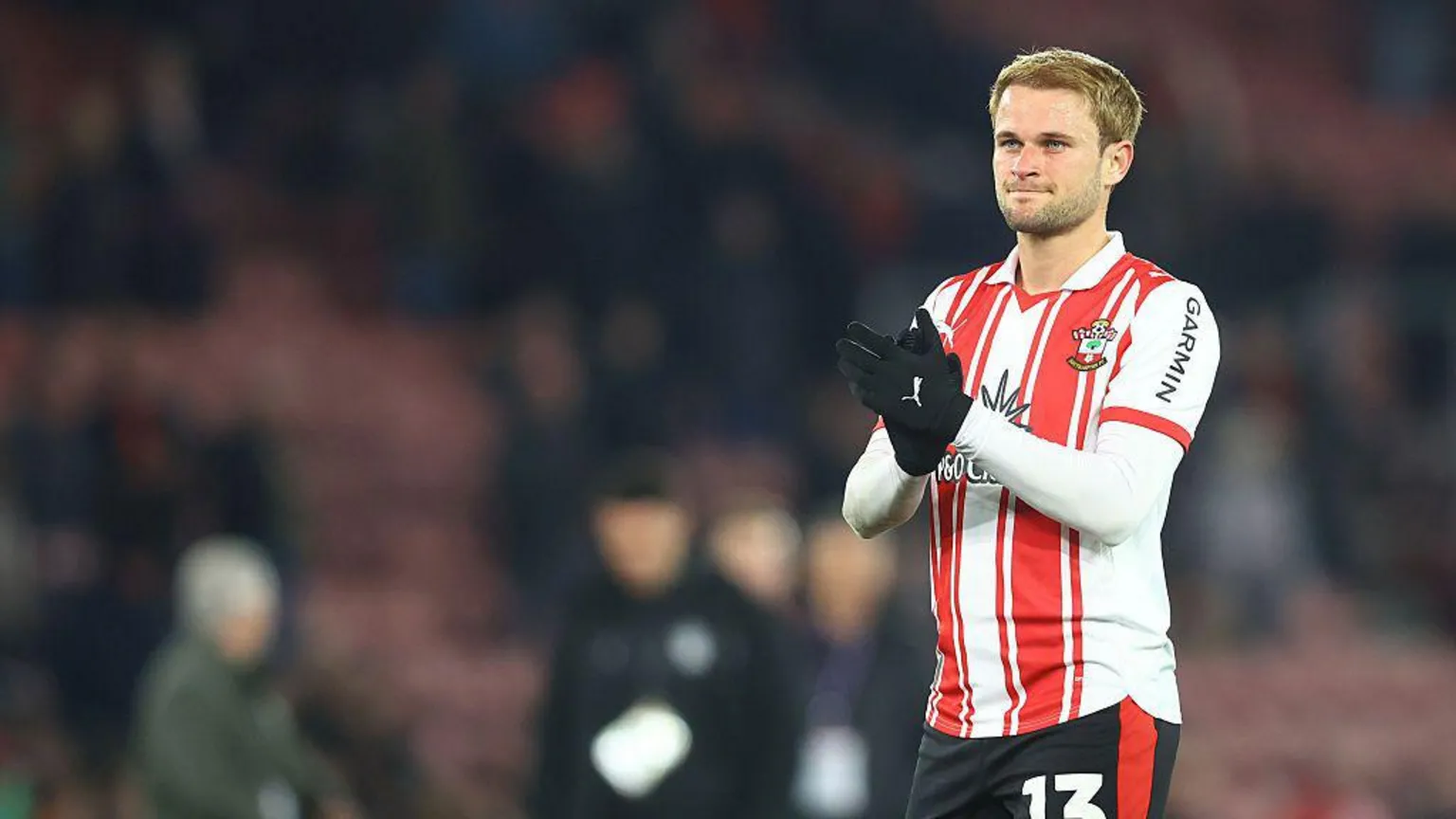Léo Scienza wearing a red and white saints kit and applauding the fans.