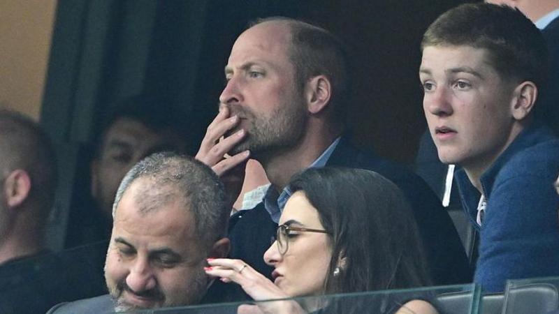 Prince William with his hand on his mouth