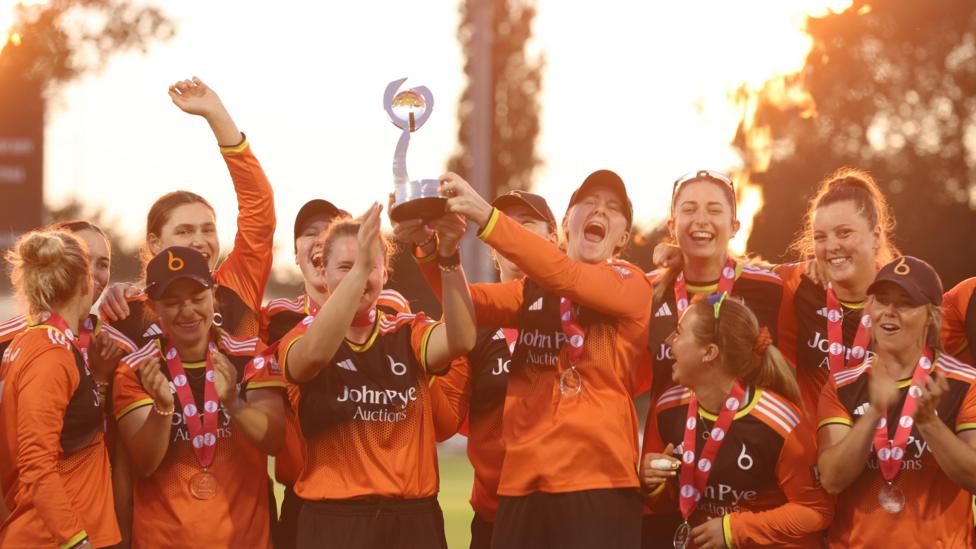 The Blaze celebrate winning the Charlotte Edwards trophy in 2026. Kirstie Gordon and Kathryn Bryce lift the trophy, whilst the team celebrates around them. 