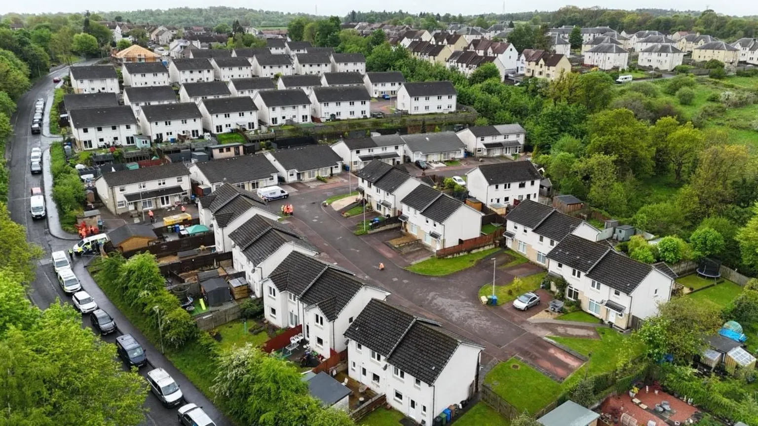 An aerial view of a residential street of white houses