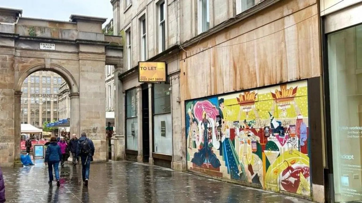 Wide street view of Exchange Place in Glasgow showing a colourful mural covering the boarded frontage of Rogano restaurant, with pedestrians walking past and a stone archway in the background.