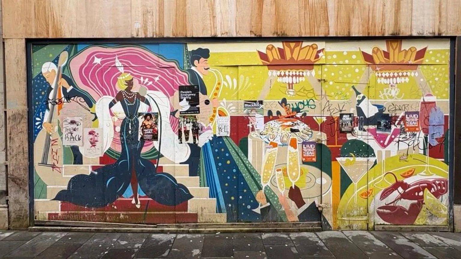 Colourful mural covering the exterior of Rogano restaurant, depicting art deco styled figures, champagne glasses, seafood, and the large red lobster from it's logo, with graffiti and posters layered across the artwork.