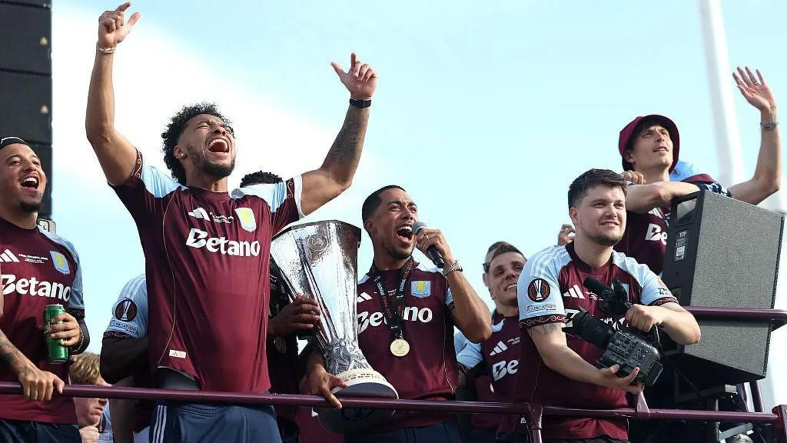 Villa players cheer and celebrate on top of a bus.