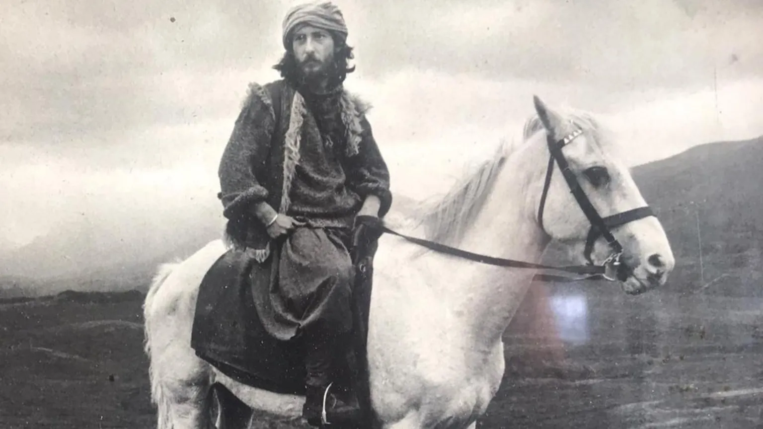 Holmes Family A black and white picture of a man on a white horse. He has a long beard and is dressed in dark robes.