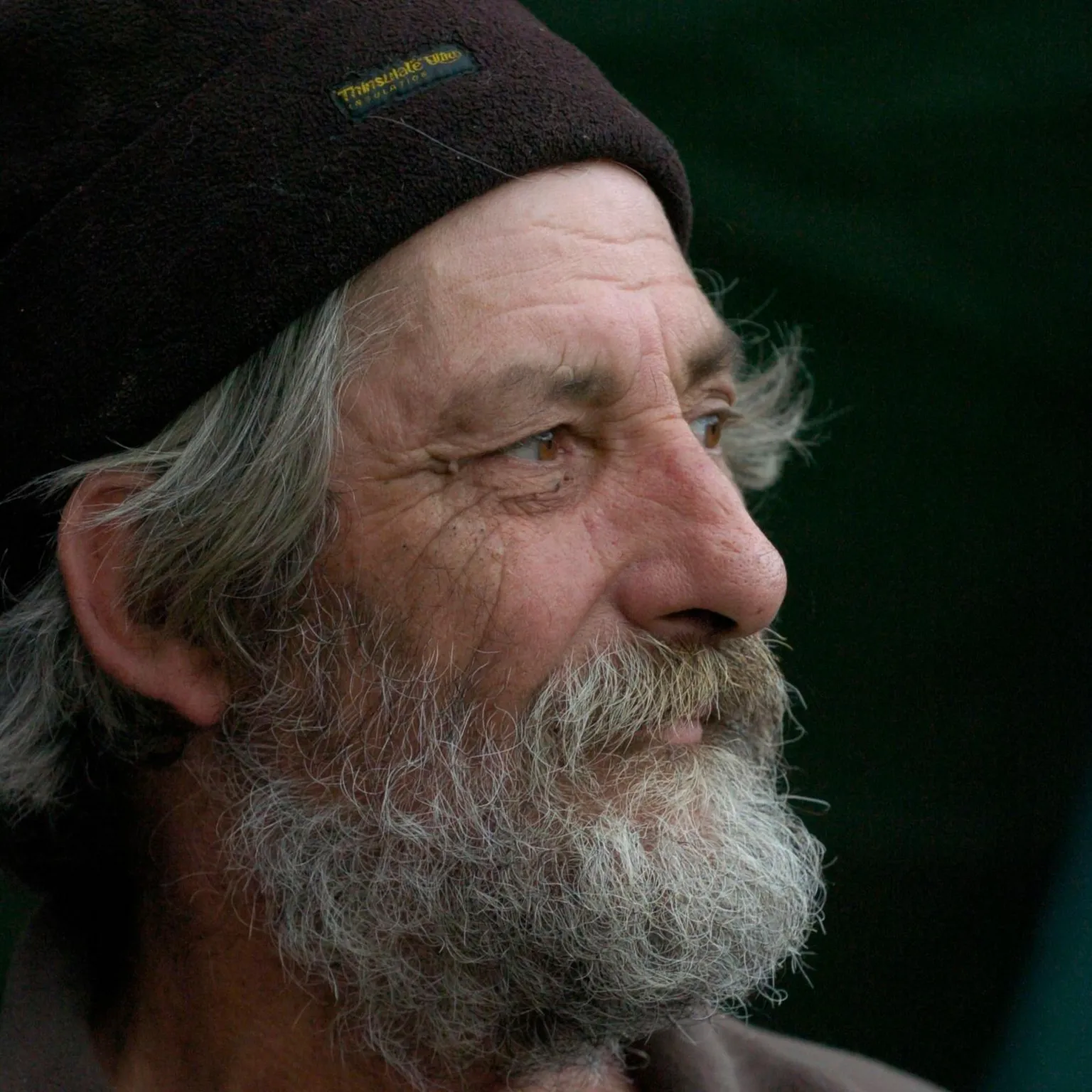 Holmes Family A man with a black woolly hat on and a grey beard looks off to the right