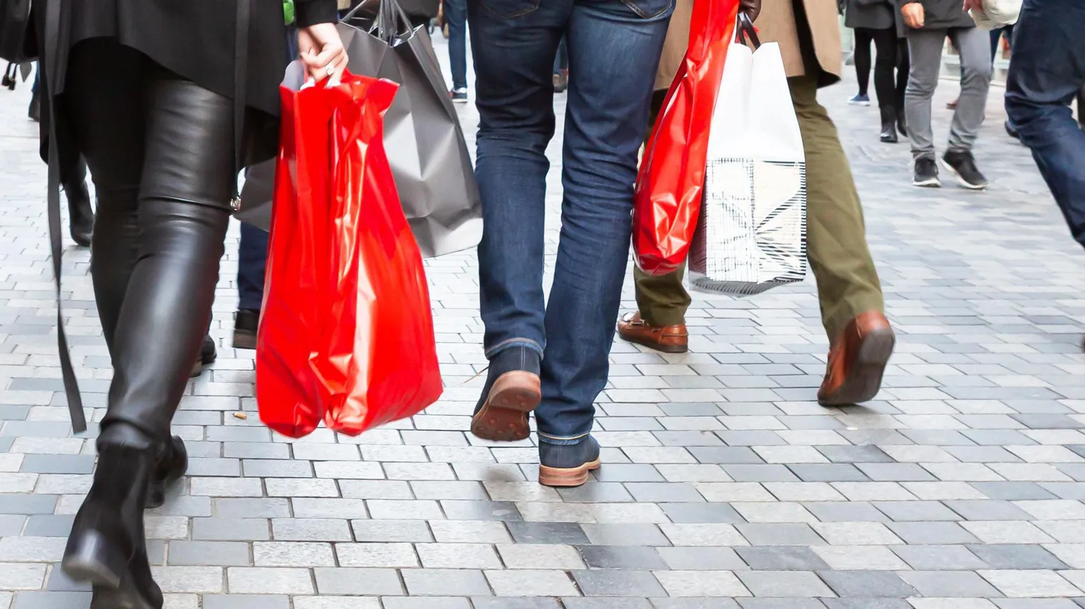  People walking with shopping bags. Shot of people's legs. 