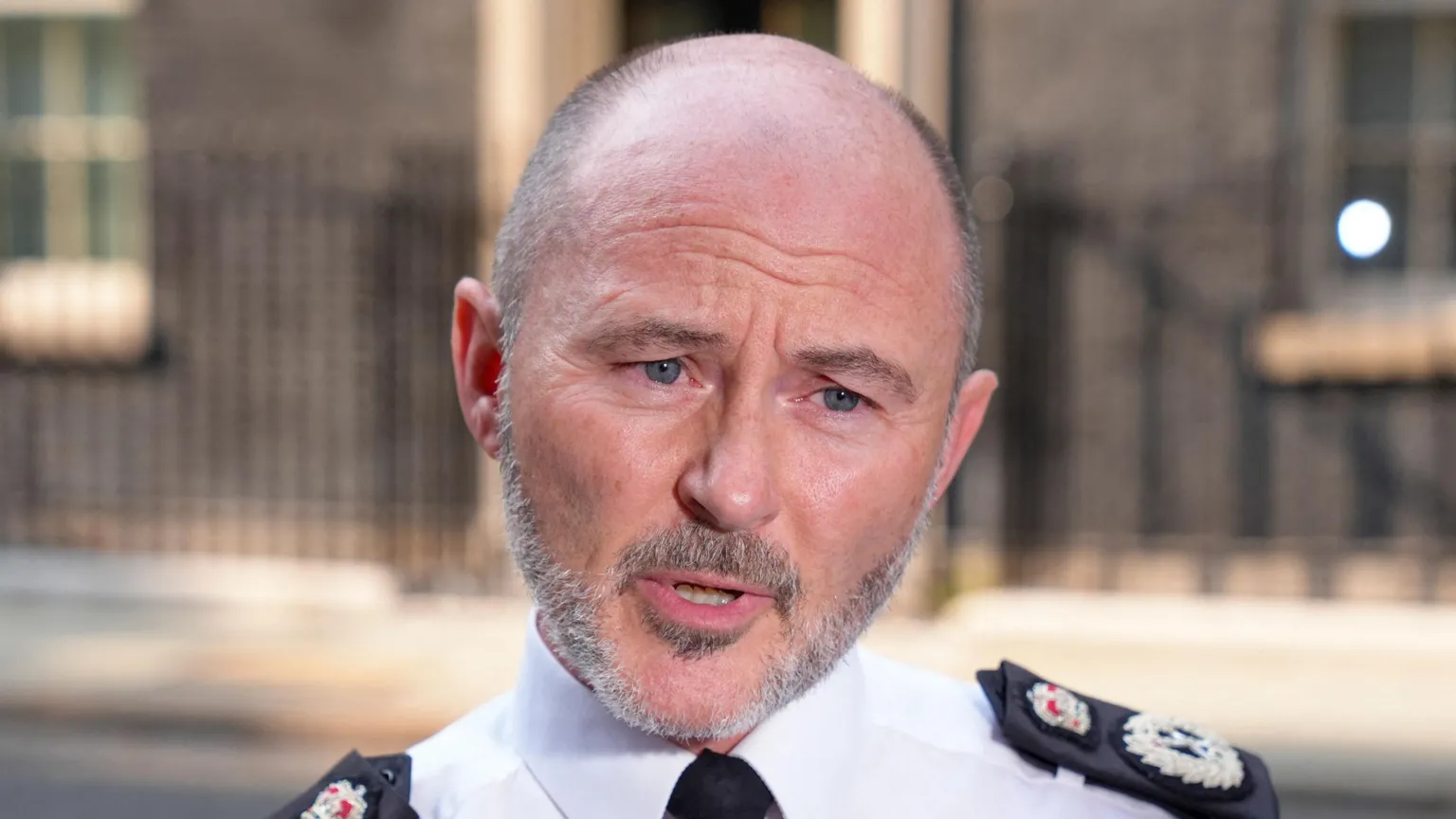 A head and shoulders pictures of Chief Constable Gavin Stephens, he is in uniform speaking at an earlier unrelated interview outside downing street which is visible blurred in the background