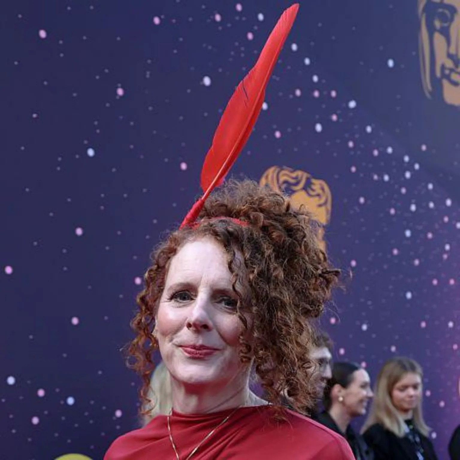 Maggie O'Farrell in a red dress with a red quill headpiece