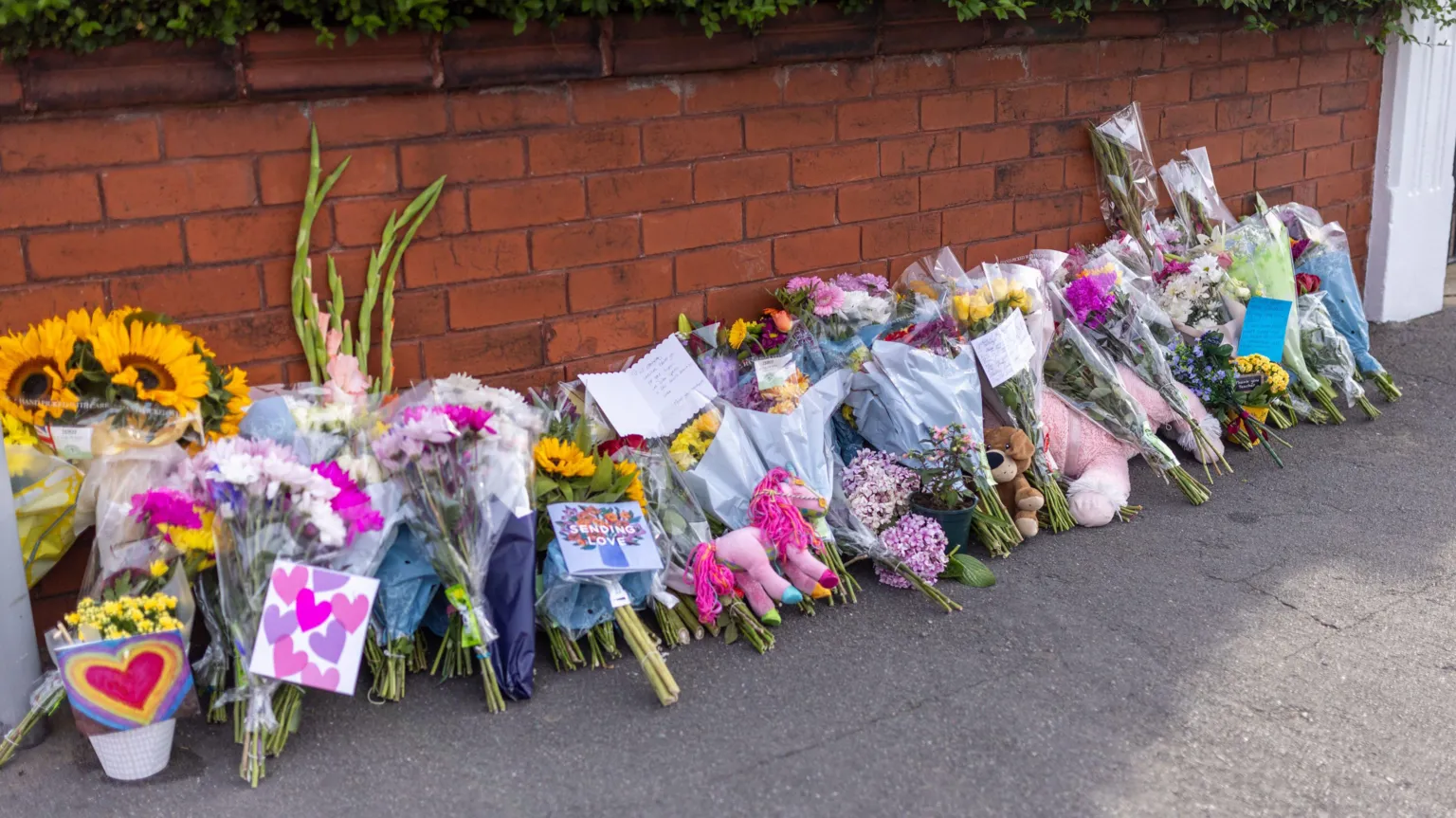 James Speakman/PA Wire Floral tributes lined up against a brick wall near the scene in Hart Street, Southport