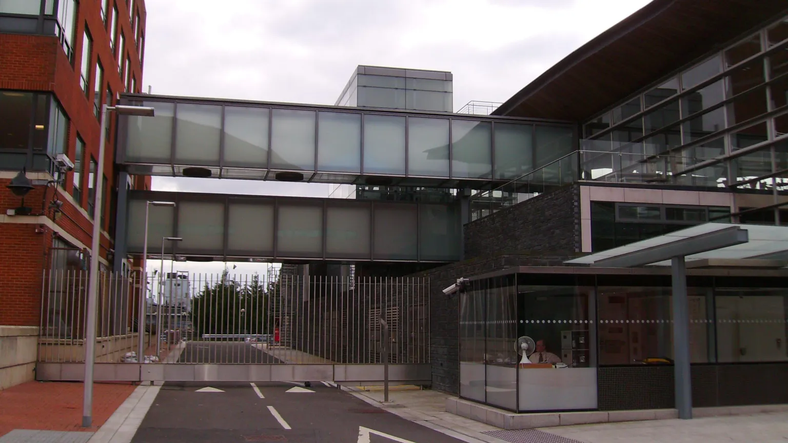 Seth Whales The image shows two glass walkways connecting the red brick Tŷ Hywel building on the left and the Senedd building on the right.