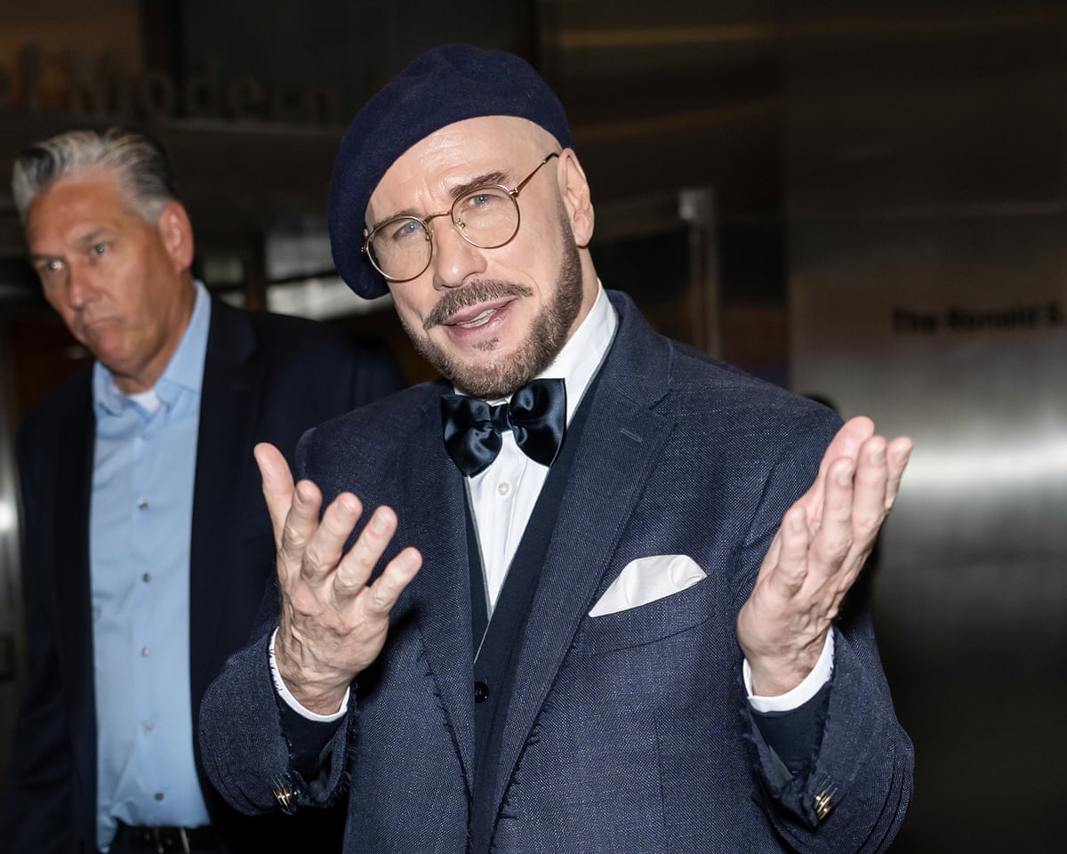 John Travolta in beret and glasses and suit at the premier of Propeller One-Way Night Coach in New York.