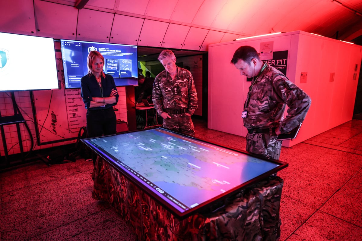 Military personnel look over a large digital map in the command centre