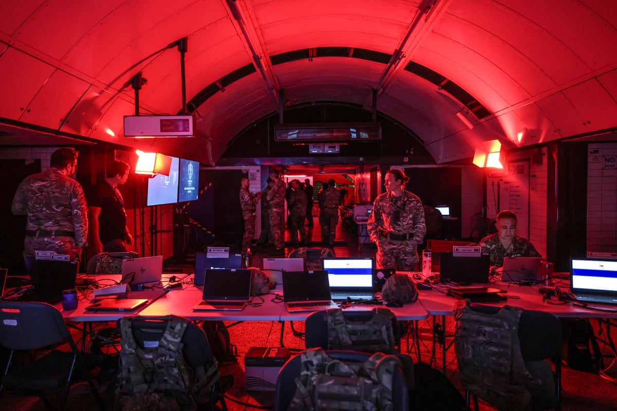 Soldiers in a red-lit room with laptops and screens