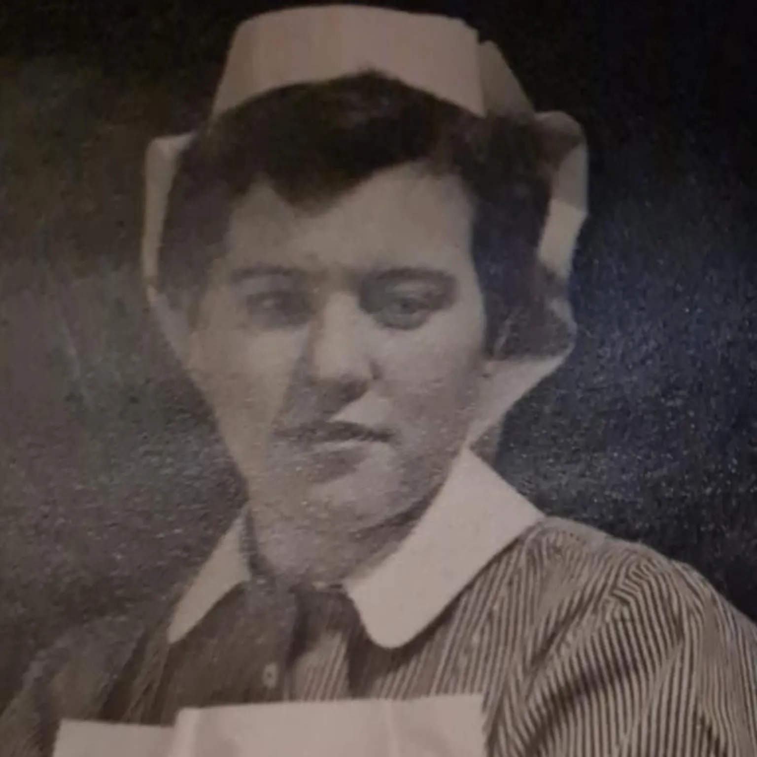 Fiona Brown A black and white photograph of an adult Moira wearing nurse scrubs.