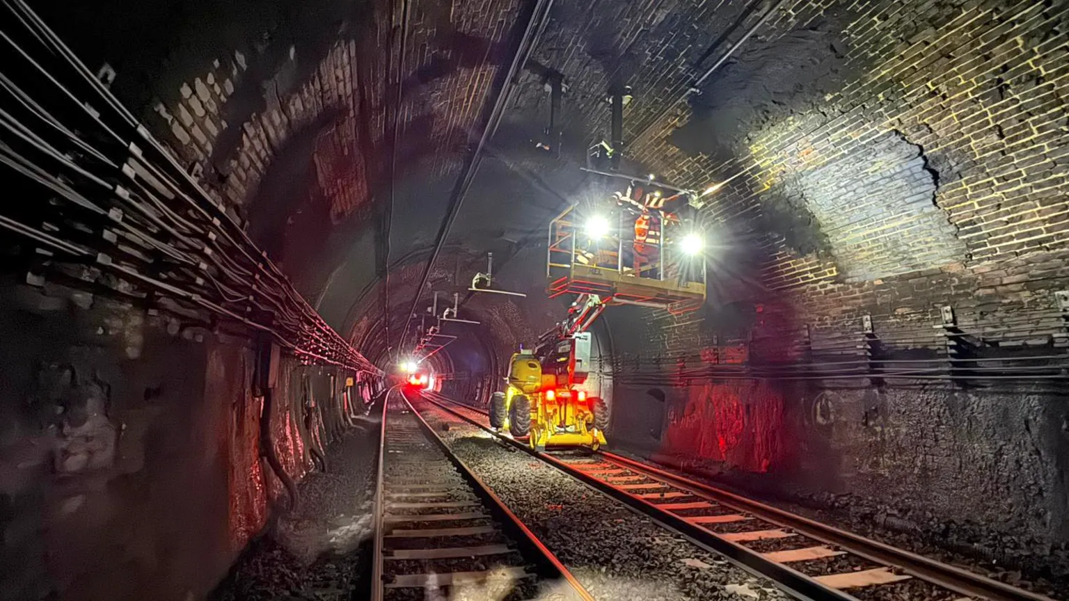 Network Rail Workers on crane lifts inside the Severn Tunnel replace the overhead lines inside the tunnel