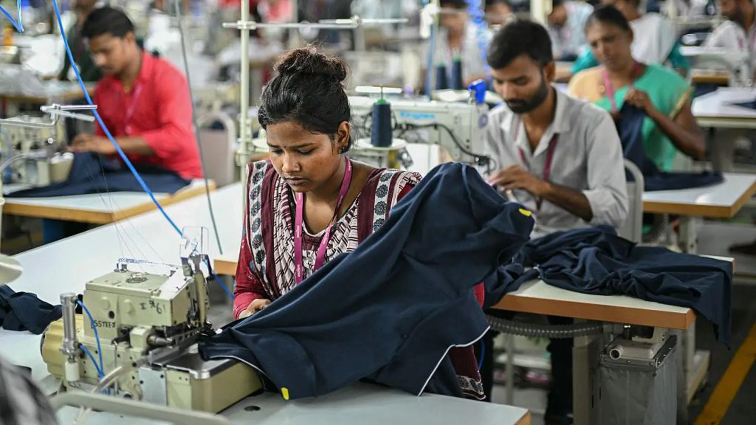 AFP via A woman employee wearing a red traditional Indian suit work at a garment factory in Tiruppur, in India's southern state of Tamil Nadu