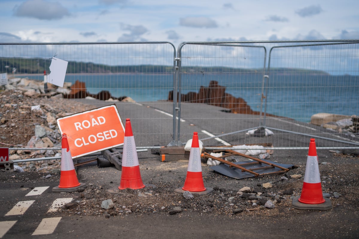 A destroyed road at Slapton Sands with a ‘road closed’ sign and four traffic cones.