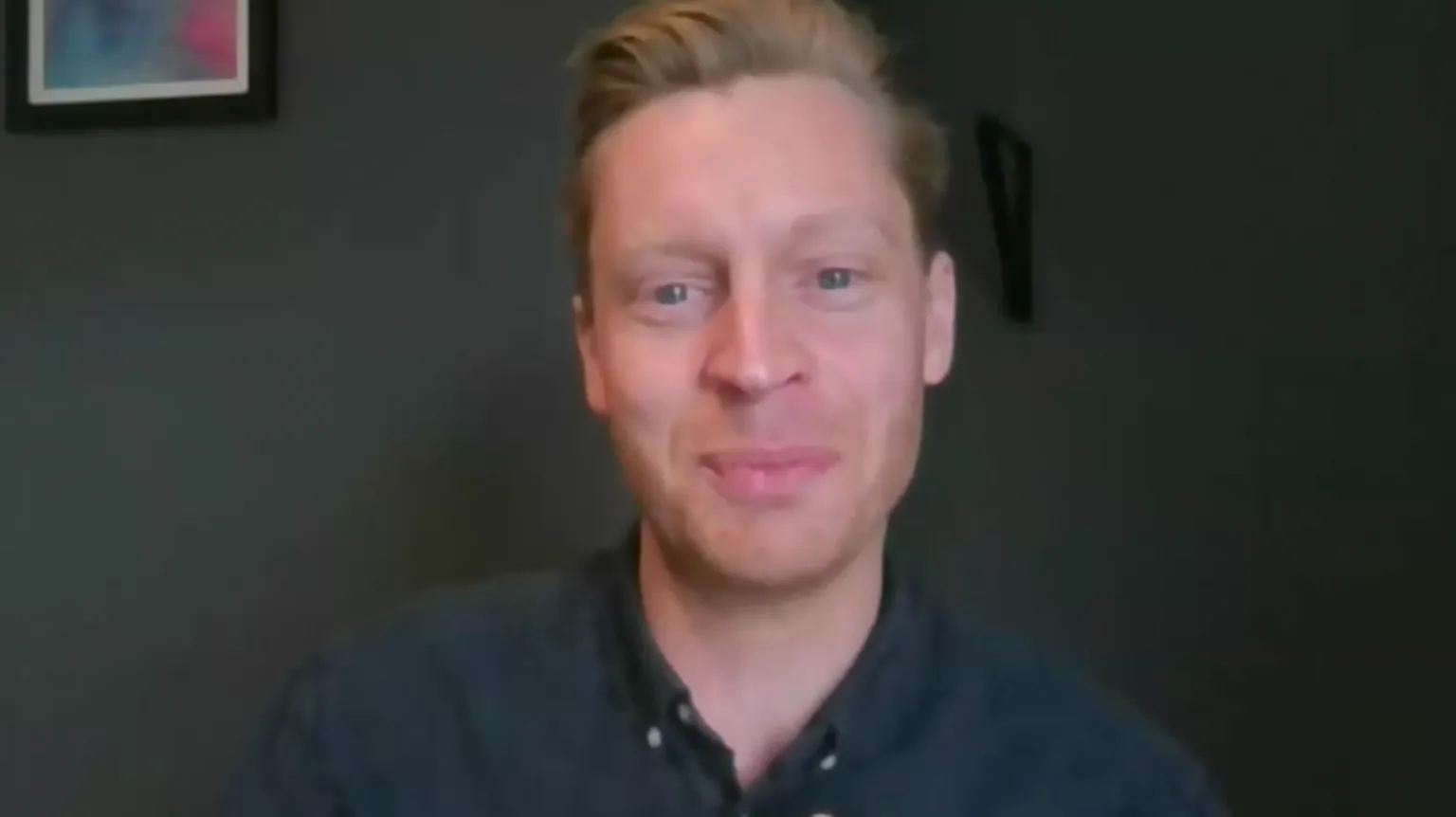 A man with a navy shirt smiles at the camera.